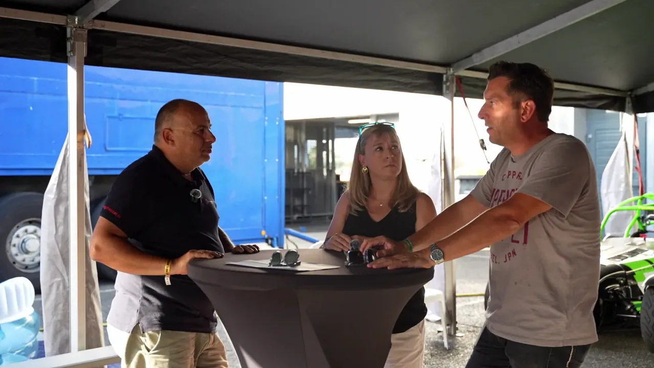 Dominique Palanque échange avec les parents d'un jeune pilote, dans le paddock