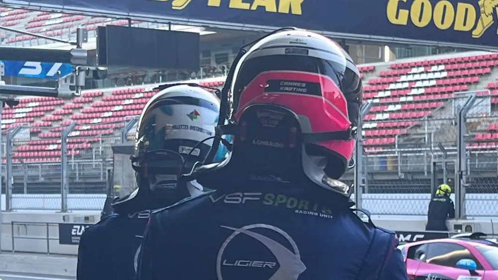 Deux pilotes casqués au muret des stands du circuit de Barcelone, pendant un week-end de course